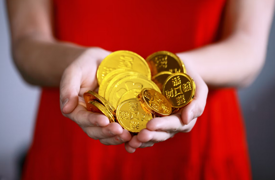 Woman in a red dress holding a handful of gold Chinese coins